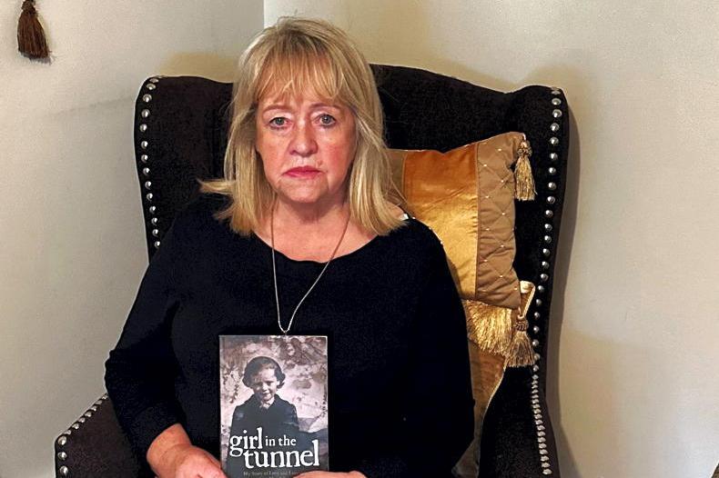 A picture of Maureen Sullivan with her book about her experience in the Magdalene laundries. 